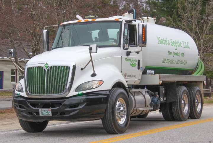 Nate's Septic LLC white septic pump truck lettered with New Ipswich, NH and the company phone numbers, parked on a roadside